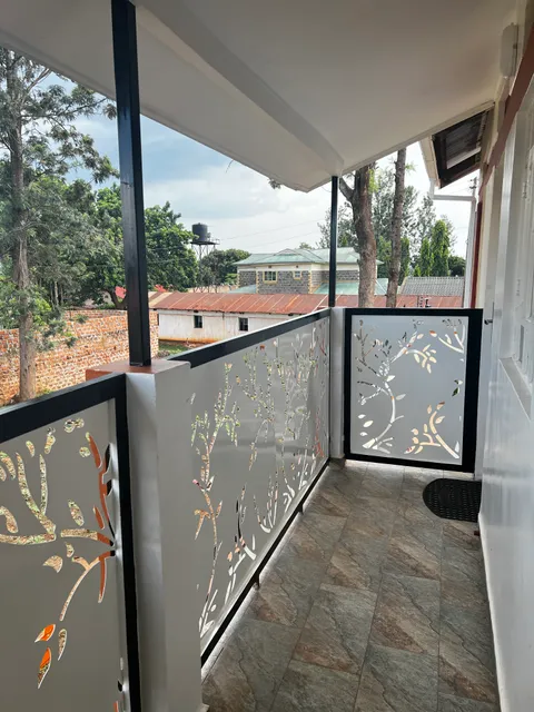 The length of Astra’s covered balcony with patterned railings, tiled floor and trees beyond.