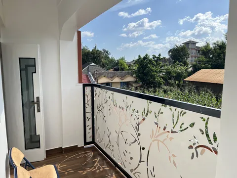 Astra balcony with patterned railings overlooking trees and nearby rooftops.
