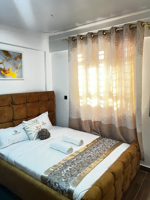 A prepared Wangs BnB bedroom with branded white bedding and folded towels.