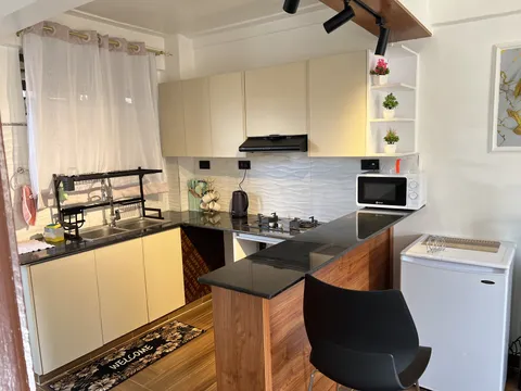 Luna kitchen with a breakfast counter, black stool, microwave, hob and cream cabinets.
