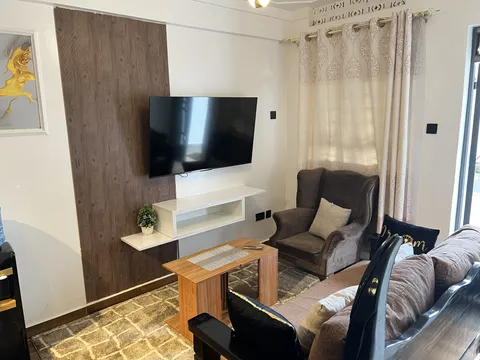 Luna living room with a sofa, armchair, wooden coffee table and wall-mounted television.