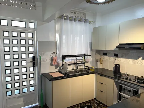 Nova kitchen with cream cabinets, a dark worktop, sink and cooking area beside a glazed door.