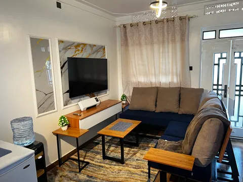 Nova living room with a corner sofa, wall-mounted television and wooden coffee tables.