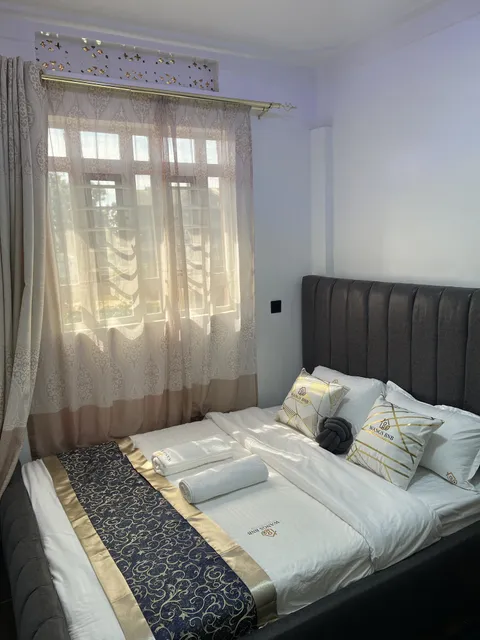 Nova main bedroom with a dark upholstered headboard, white bedding and folded towels.