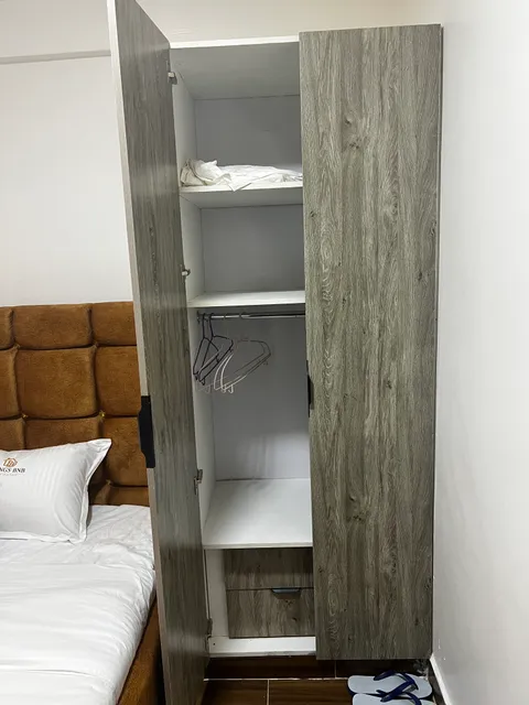 Open wardrobe beside Sol’s bed, showing shelves, a hanging rail and clothes hangers.