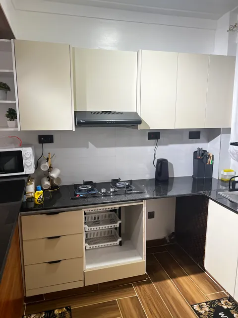 Sol kitchen with a two-burner hob, microwave, kettle, utensils and cream cabinets.