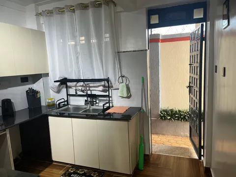 Sol kitchen sink and drying rack beside a bright window and the open kitchen door.