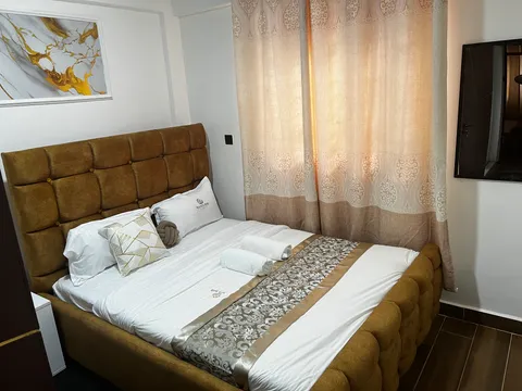 Sol main bedroom with a golden-brown upholstered headboard, white bedding and rolled towels.