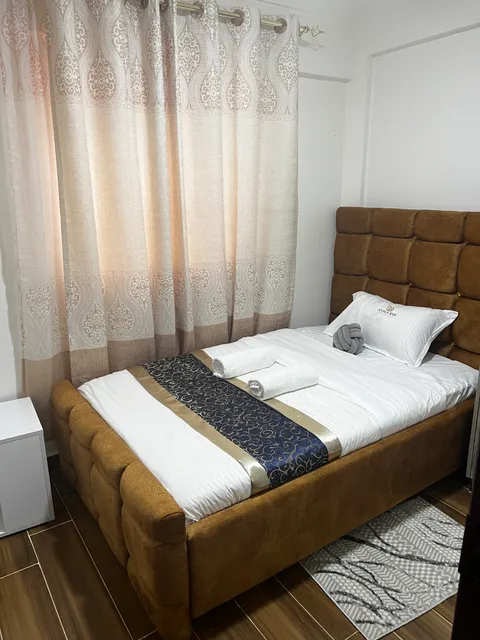 Sol second bedroom with a single bed, white bedding, a patterned runner and curtains beside the window.