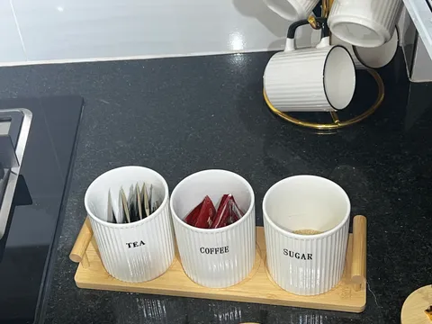 Tea, coffee and sugar containers on a wooden tray on Sol’s kitchen worktop.